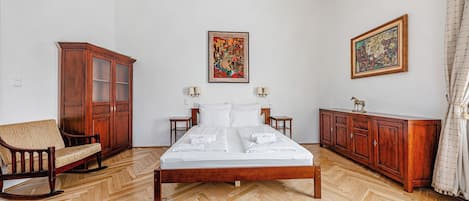 A hotel room with a wooden bed, a sofa, a cabinet, and a rug.