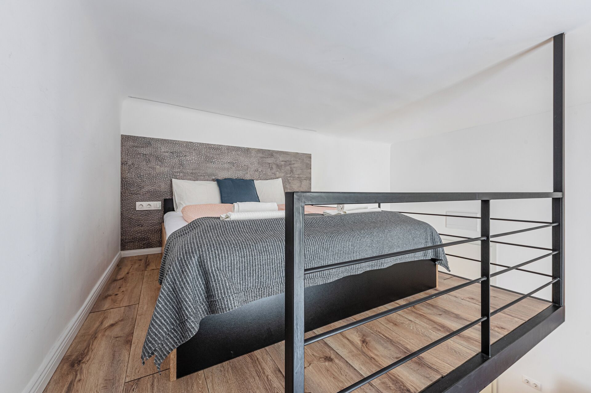 Camera da letto con un letto, una testiera e un pavimento in legno.