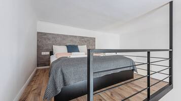 Camera da letto con un letto, una testiera e un pavimento in legno.