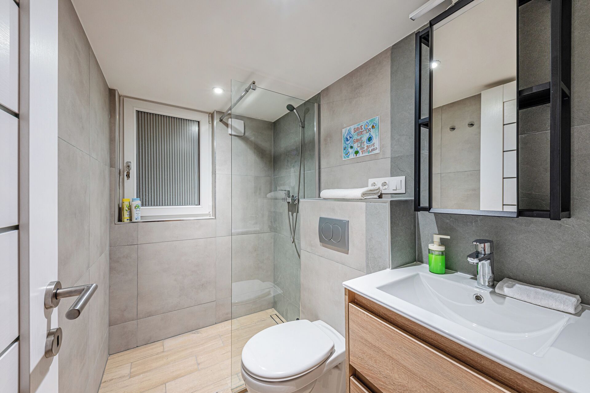 A modern bathroom with a shower, toilet, sink, and a large mirror.