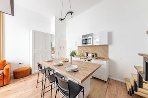 Une cuisine moderne dotée d’un îlot central en bois, de meubles blancs et d’un four à micro-ondes encastré.