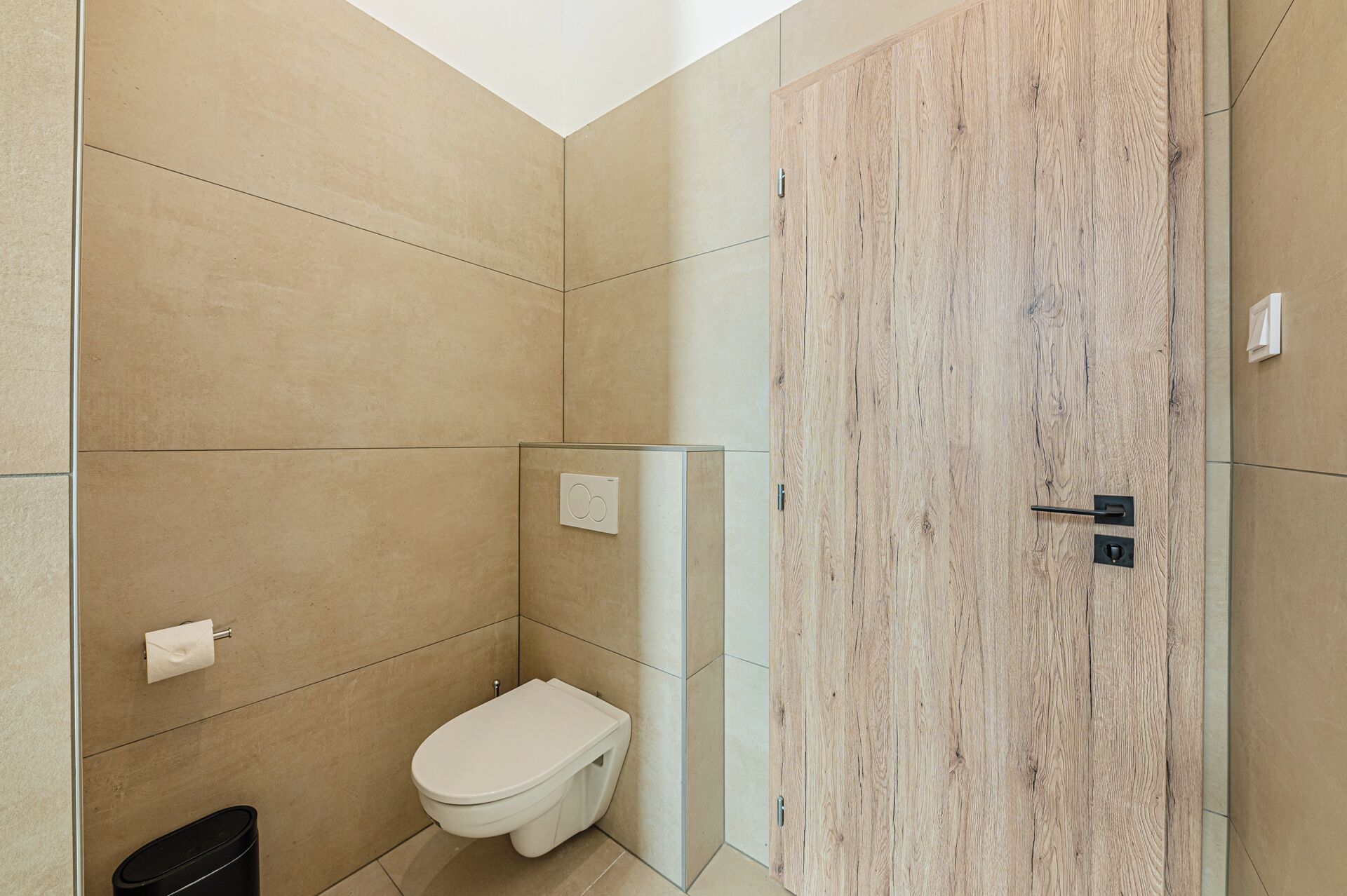 A modern bathroom with a toilet, a shower, and a wooden door.
