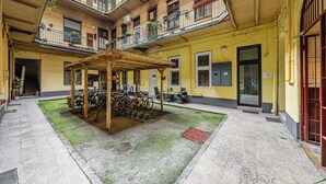A courtyard with a wooden pergola, bicycles, and a building with balconies and windows. - Marble Royal Suite&Studio (Budapest)