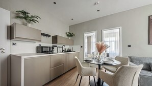 Une cuisine moderne avec un coin repas, comprenant une table ronde avec des chaises, un four encastré et un four à micro-ondes.