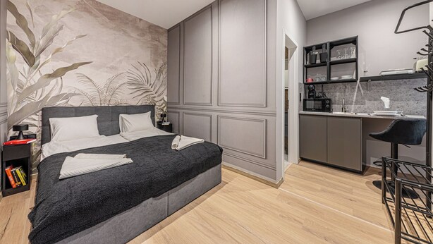 Une chambre moderne avec un grand lit, un petit bureau et un coin cuisine.