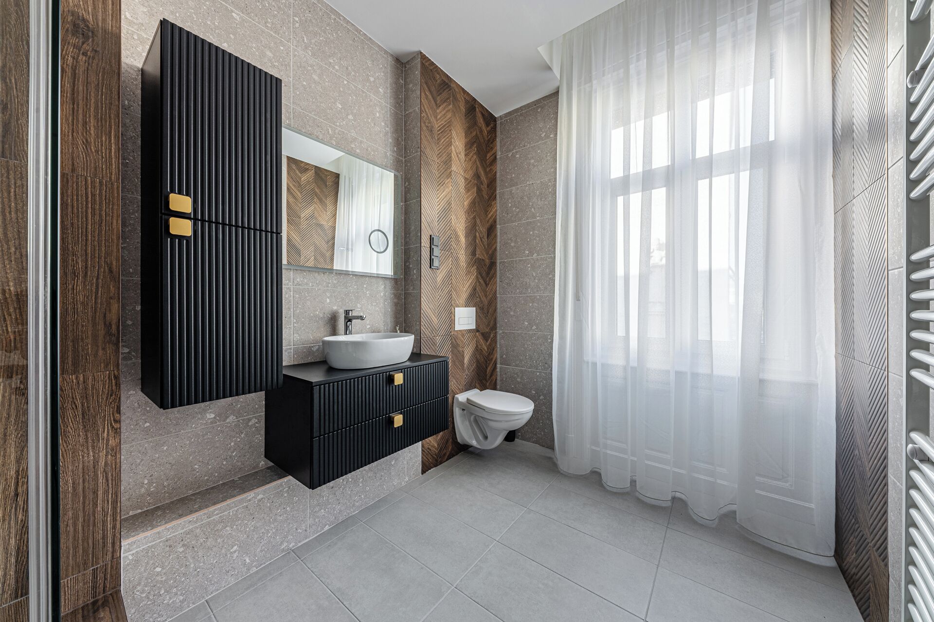 A modern bathroom with a large mirror, a sink, and a toilet.