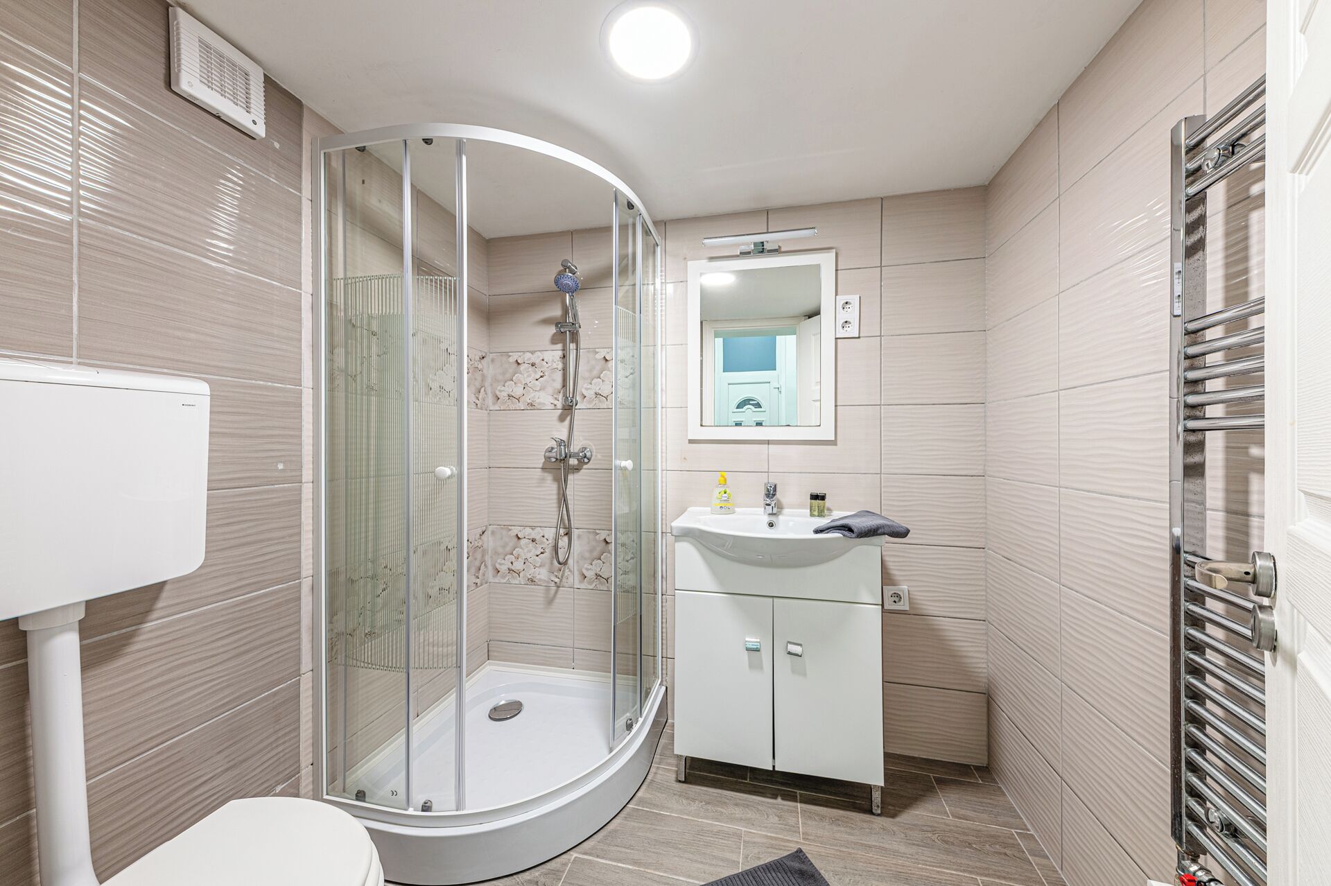 Une salle de bain moderne avec une douche à parois de verre, un lavabo blanc et des toilettes.