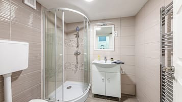 Ein modernes Badezimmer mit einer Duschkabine, einem weißen Waschbecken und einer Toilette.