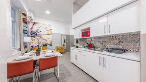 Una cocina moderna con armarios blancos, salpicadero de azulejos y un comedor con mesa y sillas.