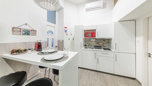Una cocina compacta con armarios blancos, microondas y salpicadero de azulejos.