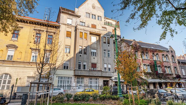 Un edificio de varios pisos con una mezcla de estilos arquitectónicos, incluyendo un edificio de esquina destacado con techo triangular y una estructura de techo plano con ventanas amplias.