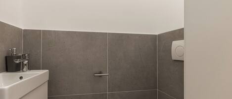 A bathroom with a toilet, a sink, and a shower area.