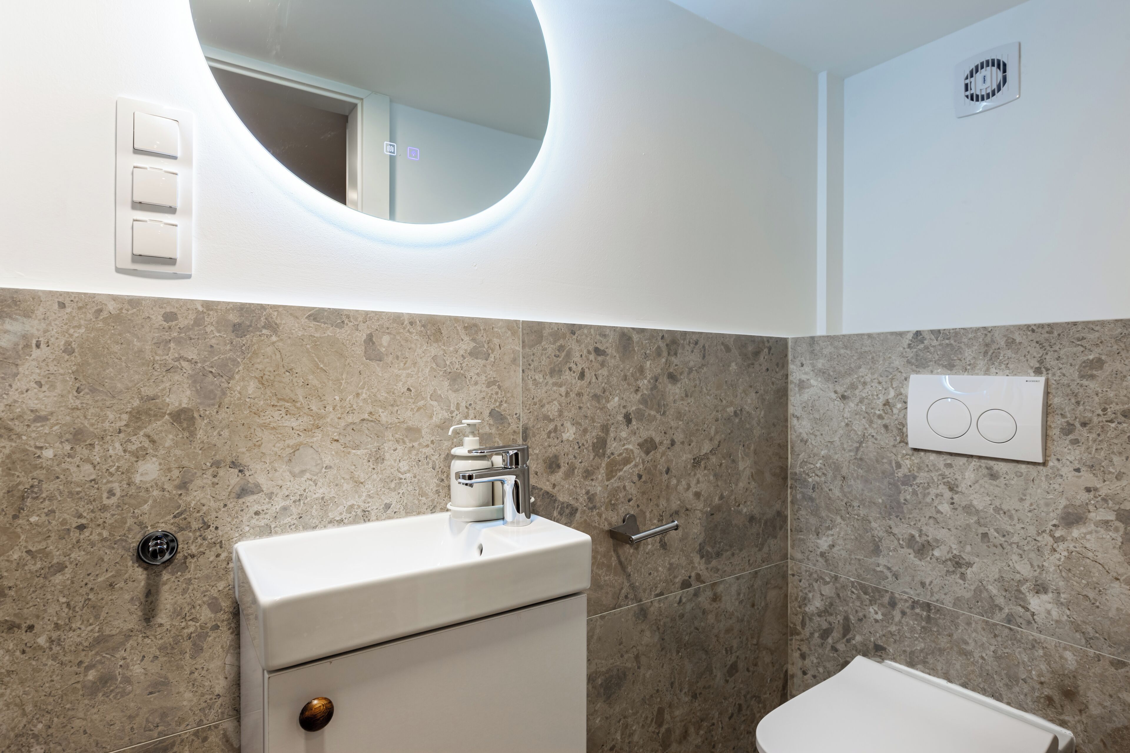 Un baño con lavamanos blanco, espejo, inodoro y ducha.