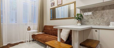 A modern kitchen with a white countertop, a brown sofa, and a white chair.