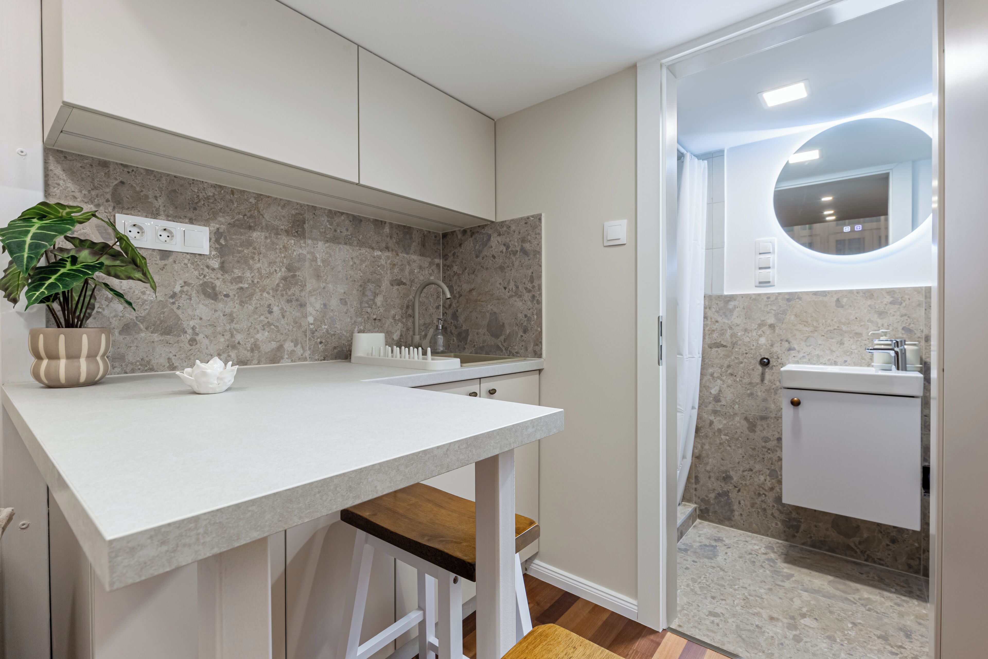 Una cocina moderna con encimera blanca, un fregadero y un espejo.