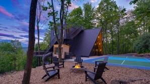 Una cabaña moderna con terraza, mobiliario exterior y una chimenea.