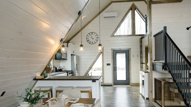 Una cocina moderna con comedor, paredes de madera, un reloj y una escalera.