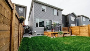 A residential building with a fenced backyard, a wooden deck, and a staircase leading to a second-story balcony. - Casa de Lex (Calgary)