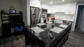 A modern kitchen with stainless steel appliances, a marble countertop, and a small exercise ball. - Casa de Lex (Calgary)