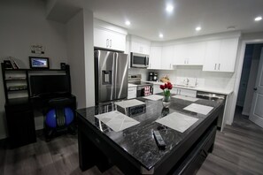 Uma cozinha moderna com armários brancos, eletrodomésticos de aço inoxidável e bancada de mármore.