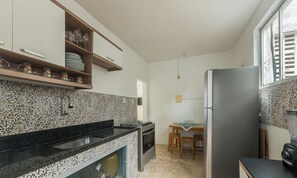 Una cocina con protector mural de azulejos, un refrigerador de acero inoxidable y un comedor con mesa y sillas.