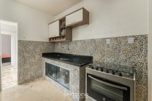 Una cocina con encimera de granito, horno empotrado y salpicadero con diseño de mosaico.