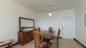 A dining area with a wooden table, chairs, a cabinet, and a mirror. - 3-bedroom Apt and Ocean View Edi0302 (Salvador)