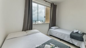 A hotel room with two beds, a window with curtains, and a view of the sea. - 3-bedroom Apt and Ocean View Edi0302 (Salvador)