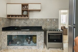 Una cocina con estufa integrada, horno y un armario de almacenamiento con puerta de vidrio.