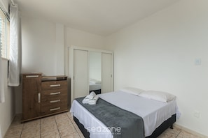 A bedroom with a bed, a wooden dresser, a mirror, and a window with curtains. - 3-bedroom Apt and Ocean View Cne0302 (Salvador)