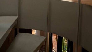 Una habitación con piso de madera, una ventana con cortinas y una puerta con marco azul.