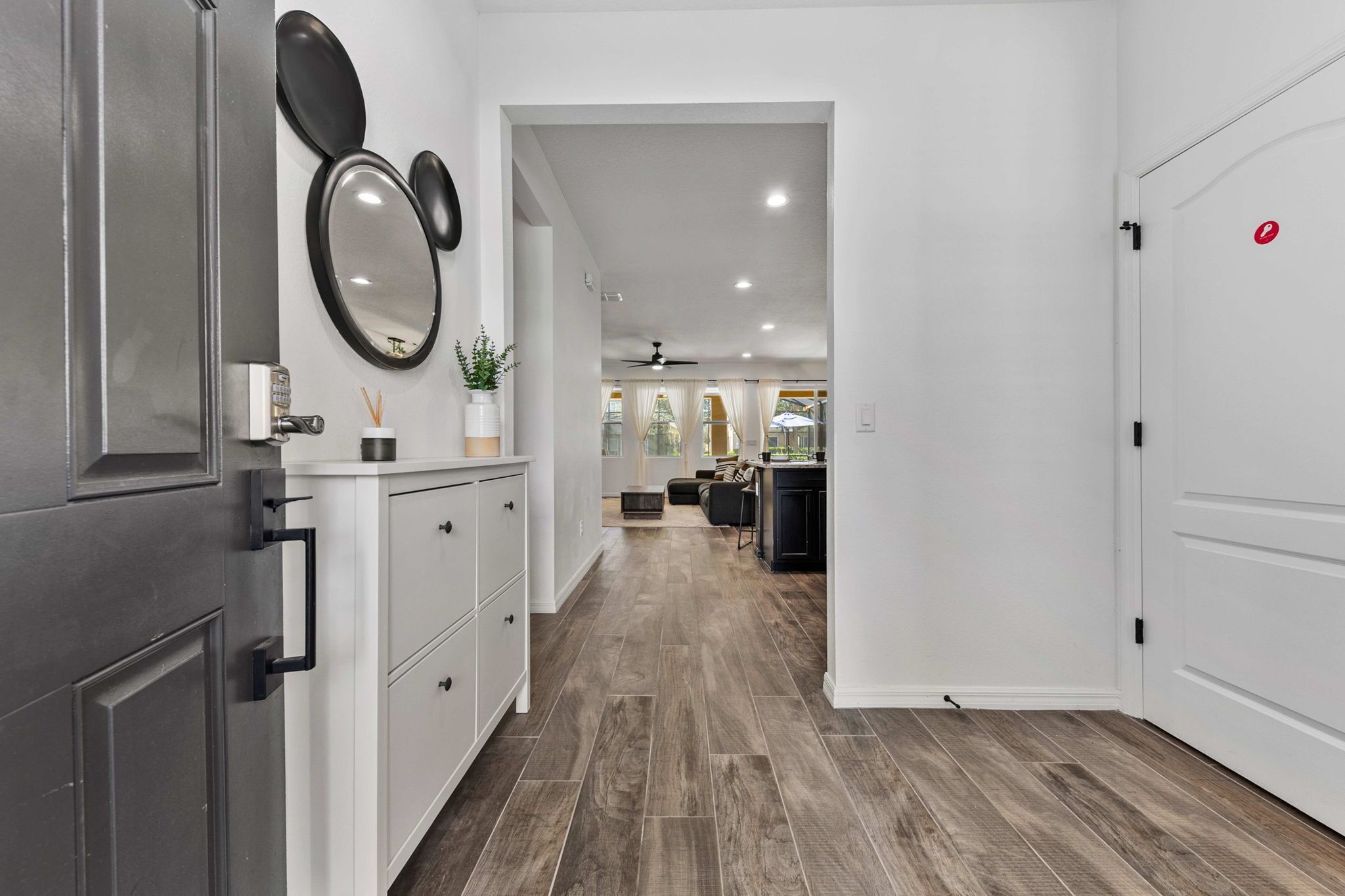 A modern kitchen with white cabinets, a black door, and a wooden floor.