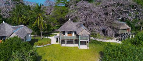 A beachfront property with thatched-roof cottages, a sandy beach, and lush greenery.