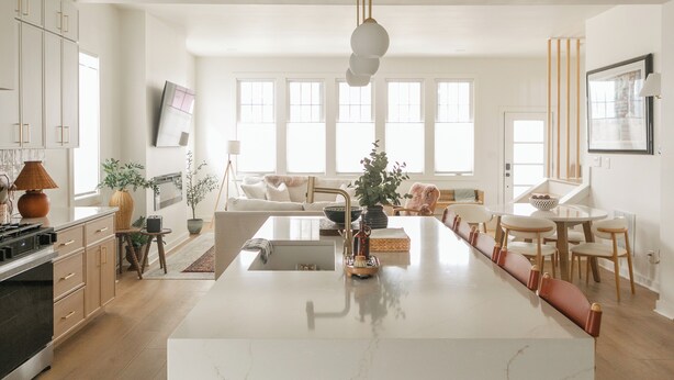 Une cuisine moderne dotée d’un îlot central, de meubles blancs et d’un coin repas avec une table ronde et des chaises.