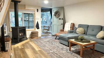 A cozy living room with a fireplace, a sofa, a rocking chair, and a view of the outdoors.