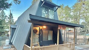 A modern, two-story cabin with a sloped roof, a wooden porch, and a small deck area. - Adventure's Retreat for Trails & Forest Fun! (Overgaard)