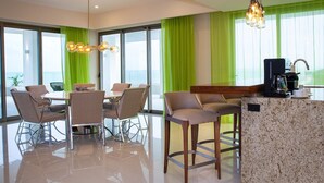 Een moderne hotelkamer met een zithoek, een keukenbar en uitzicht op de oceaan.