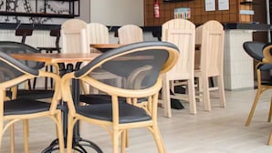 Interior de restaurante con techo alto, sillas de madera, una mesa central para comer y una pared decorada con diversos objetos.