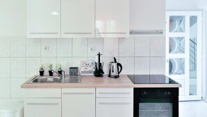 Une cuisine moderne avec des meubles blancs, un évier en acier inoxydable, une machine à café et un lave-vaisselle.