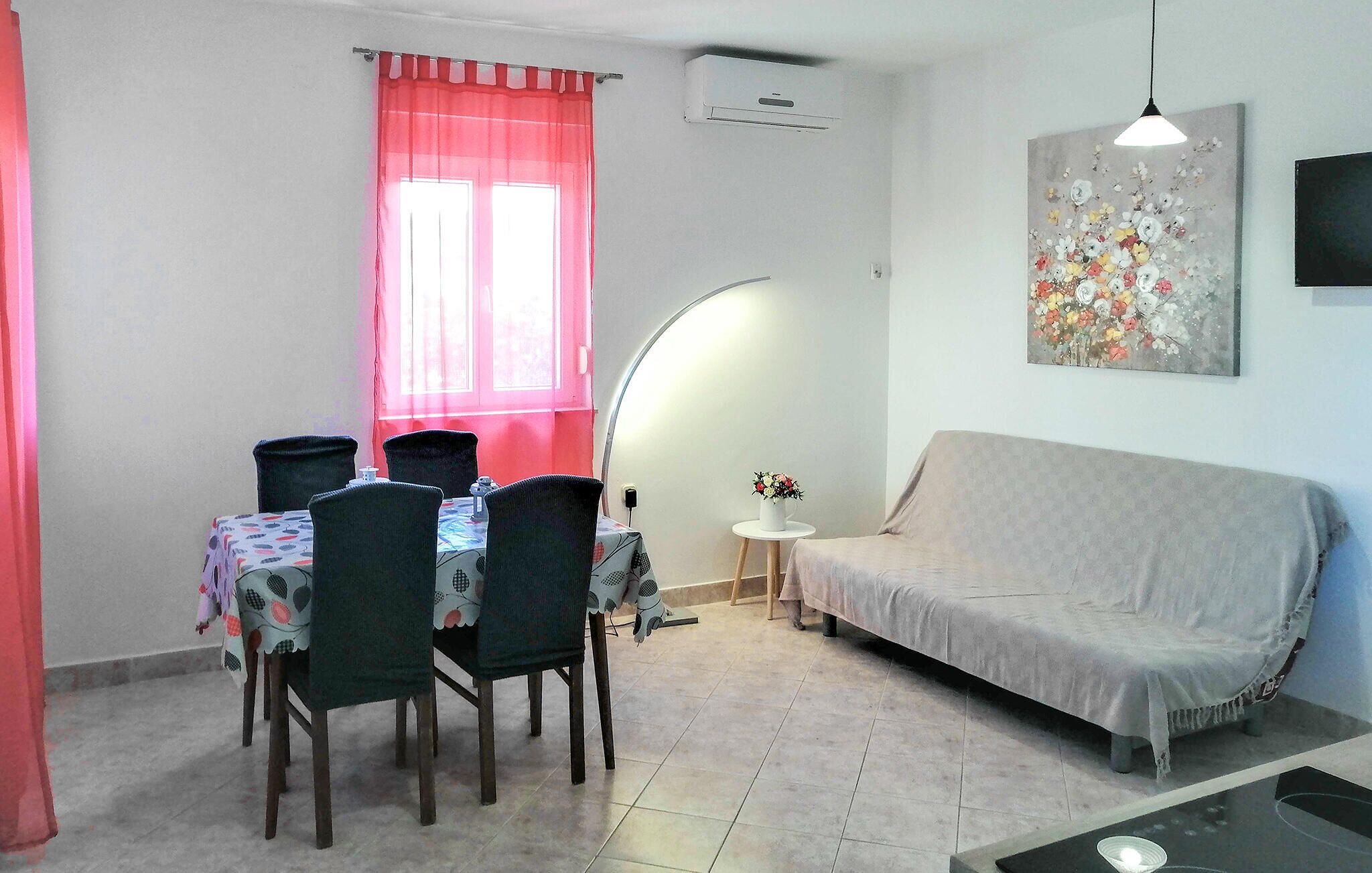 Un coin repas avec une table et des chaises, un canapé, une petite table d’appoint avec un vase et un tableau au mur.