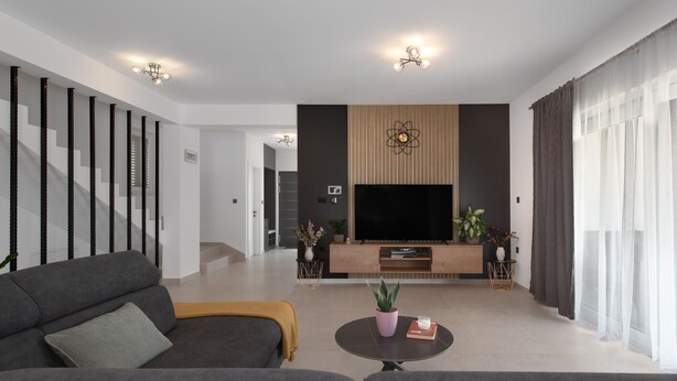 Ein modernes Wohnzimmer mit einer Couch, einem Couchtisch, einem Fernseher und Zimmerpflanzen.