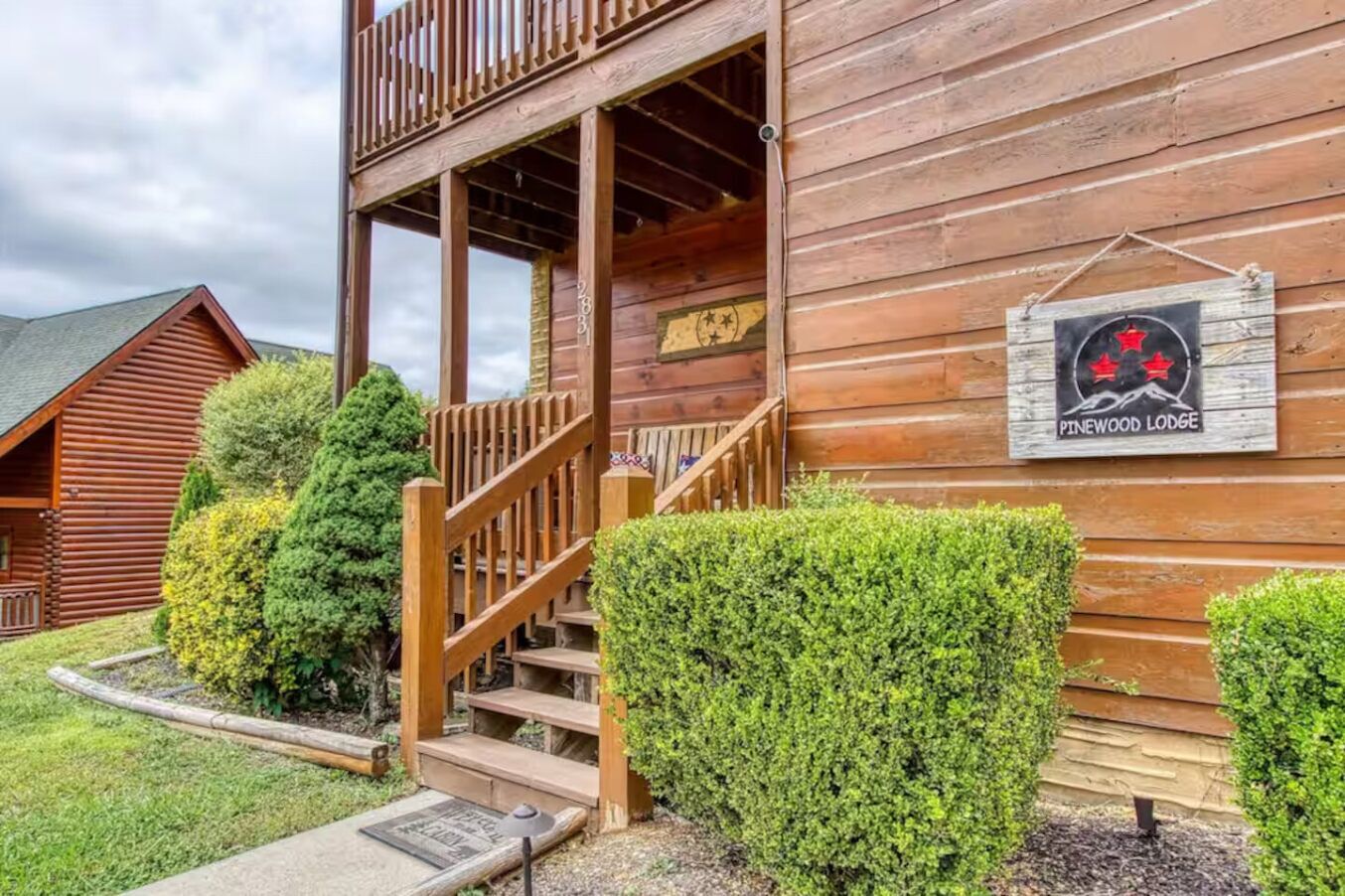 Egy fából készült, verandás, lépcsővel ellátott ház, amelyen egy tábla jelzi, hogy ez a Pinewood Lodge.