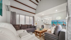 A modern living room with a sofa, a coffee table, and a gray armchair. - Cuquisastraat 30A (Oranjestad)
