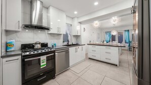 A modern kitchen with stainless steel appliances, white cabinetry, and a central island. - Cuquisastraat 30A (Oranjestad)