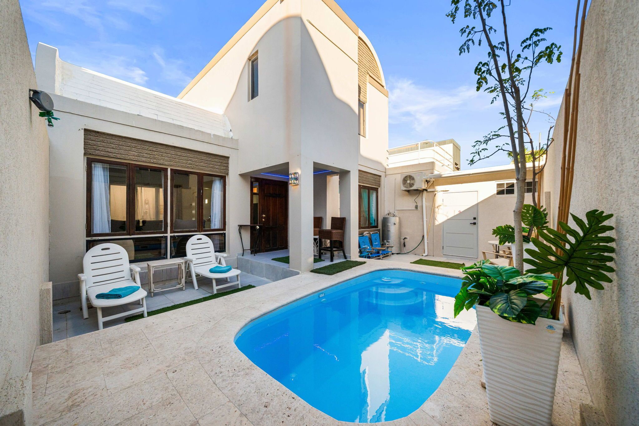 A modern villa with a swimming pool, outdoor seating, and a well-maintained garden.
