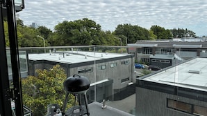 A modern building with a flat roof, a gas grill, and a gas cylinder on the balcony.