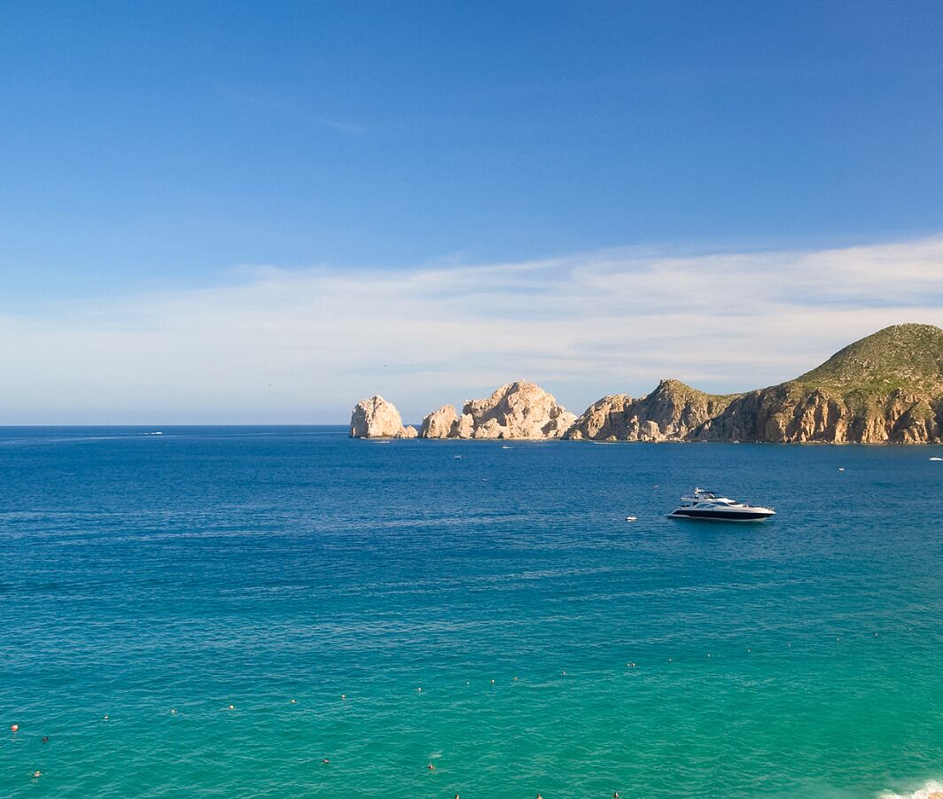 Un paysage côtier avec une eau turquoise cristalline, un yacht et des falaises rocheuses.