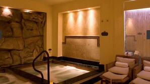 A spa room with a stone wall, a hot tub, and wicker chairs with towels. - HALF PRICE Fixed Week in Cabo San Lucas (Cabo San Lucas)