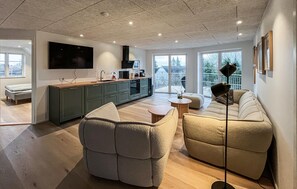 Ein modernes Wohnzimmer mit einer Couch, einem Couchtisch und einem an der Wand montierten Fernseher.