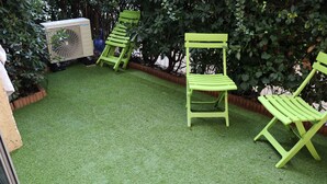 A patio with artificial grass, green chairs, and a large air conditioning unit. - Jung'Love room - Spa & Private Cinema (Saint-Cyprien)